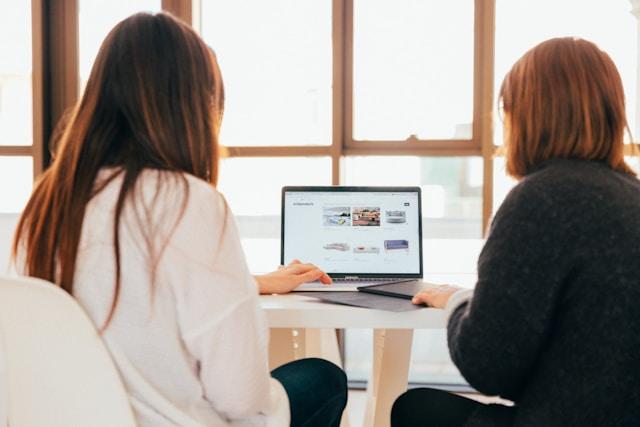 dua orang perempuan sedang membaca di laptop