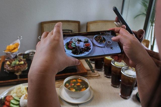 seseorang sedang memfoto nasi dan sup di atas meja